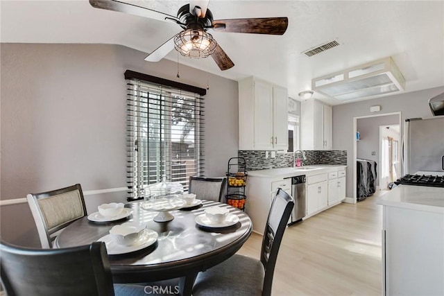 dining space featuring visible vents, vaulted ceiling, a ceiling fan, and light wood finished floors