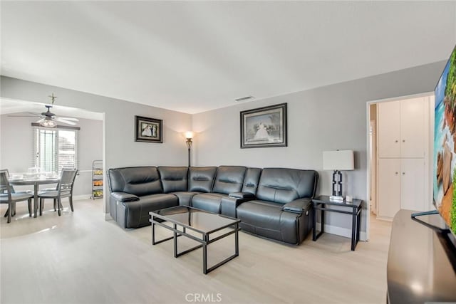 living room with ceiling fan, light wood-style floors, visible vents, and baseboards