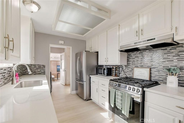 kitchen with stainless steel appliances, white cabinetry, sink, and tasteful backsplash