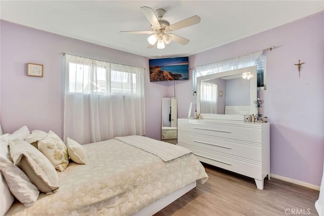 bedroom featuring baseboards, light wood-type flooring, and ceiling fan