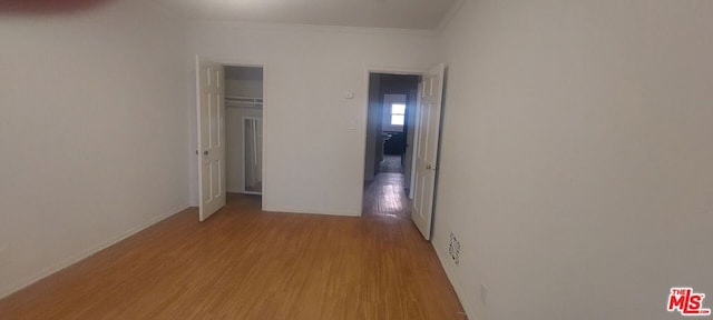 unfurnished bedroom with crown molding, light wood-type flooring, and a closet