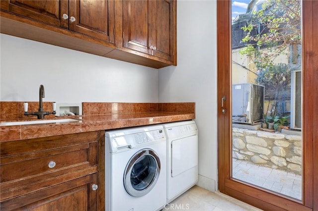 laundry area featuring cabinet space, light tile patterned floors, washer and clothes dryer, and a sink