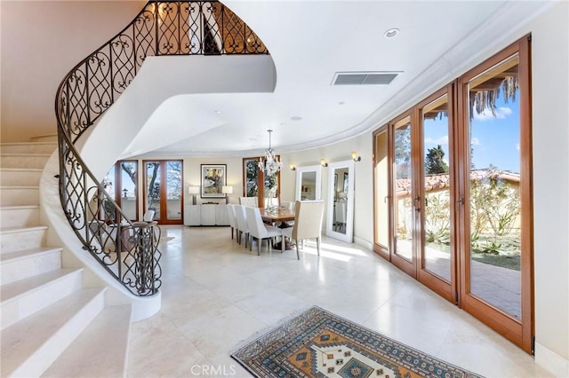 foyer featuring visible vents, ornamental molding, stairs, french doors, and a chandelier