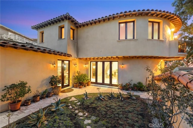 back of property with french doors, a patio, and stucco siding