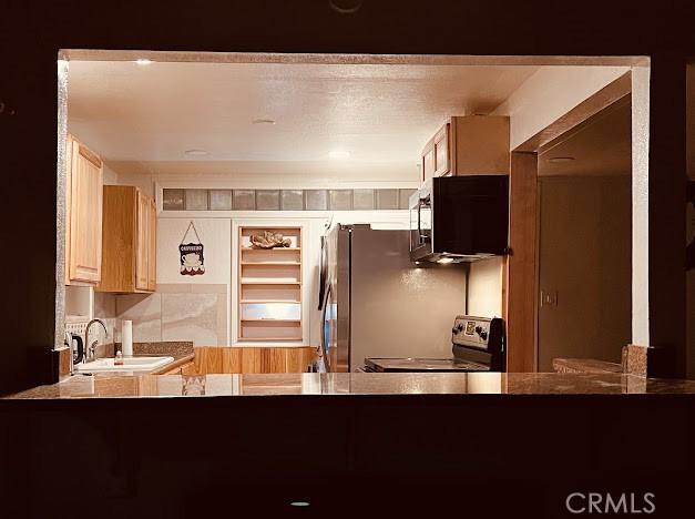 kitchen with stainless steel range with electric stovetop, sink, decorative backsplash, and light brown cabinets