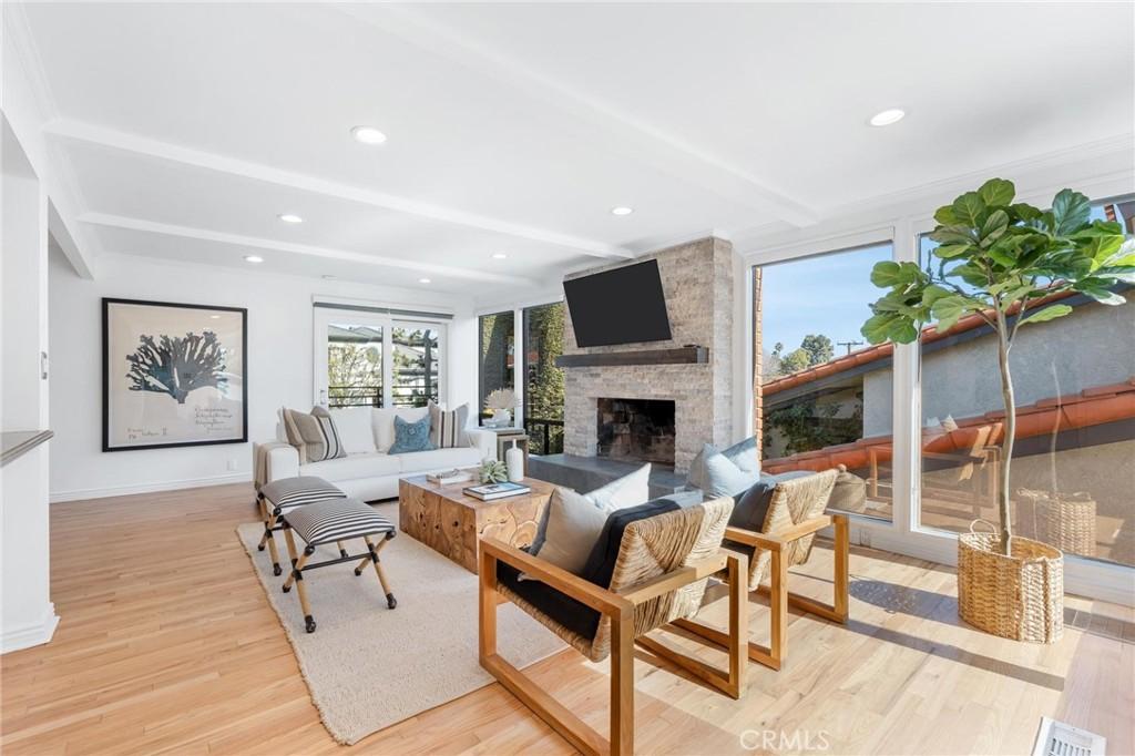 living room with beamed ceiling, a large fireplace, and light wood-type flooring