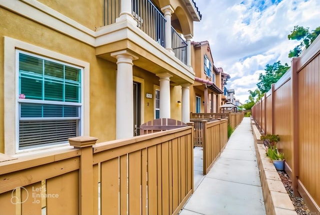 view of property exterior with fence, a balcony, and stucco siding