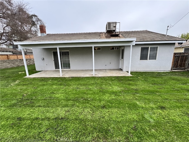 back of property with central AC, a patio area, and a lawn