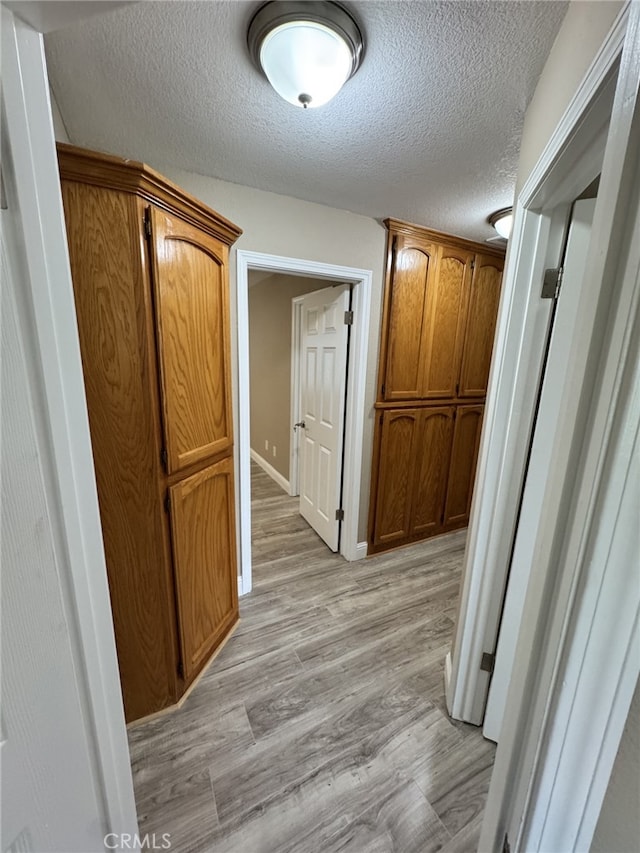 hallway featuring a textured ceiling and light hardwood / wood-style flooring