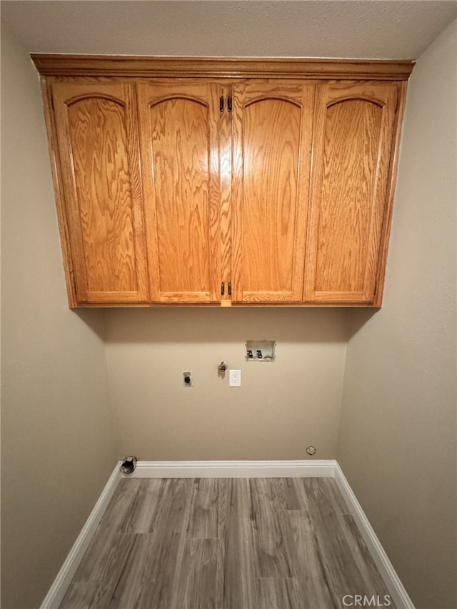 laundry room with cabinets, wood-type flooring, washer hookup, hookup for an electric dryer, and hookup for a gas dryer