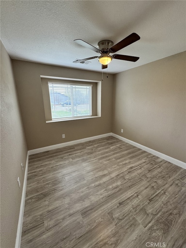 empty room with hardwood / wood-style floors, a textured ceiling, and ceiling fan