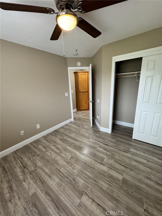 unfurnished bedroom featuring ceiling fan, hardwood / wood-style floors, and a closet