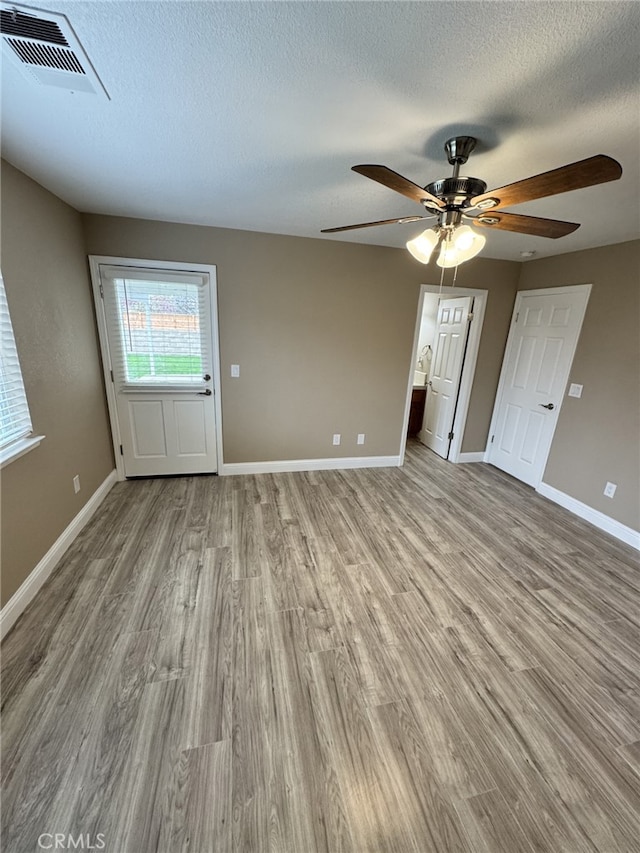 empty room with ceiling fan, a textured ceiling, and light wood-type flooring