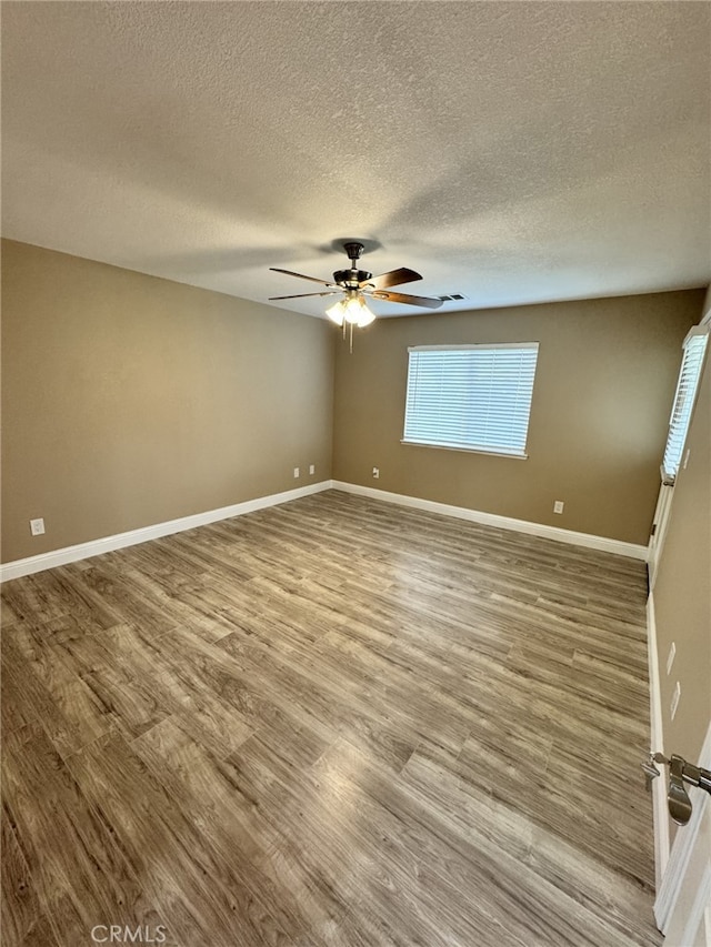 empty room with ceiling fan, hardwood / wood-style floors, and a textured ceiling