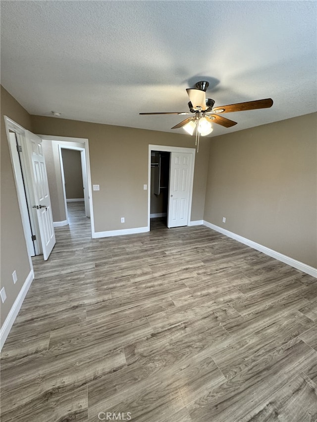 unfurnished bedroom with light wood-type flooring, a textured ceiling, ceiling fan, and a closet