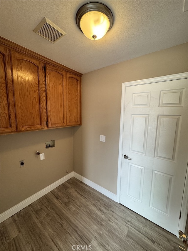 washroom with cabinets, hookup for a washing machine, hardwood / wood-style flooring, hookup for an electric dryer, and hookup for a gas dryer