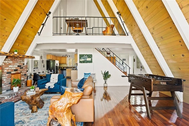 living room featuring beamed ceiling, hardwood / wood-style floors, a brick fireplace, and wooden ceiling