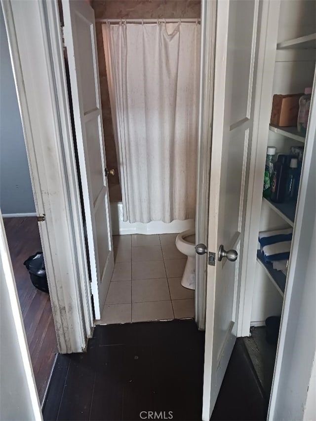 bathroom with shower / tub combo, toilet, and tile patterned flooring