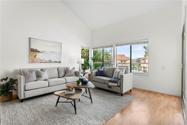 living room featuring plenty of natural light, high vaulted ceiling, and light hardwood / wood-style flooring