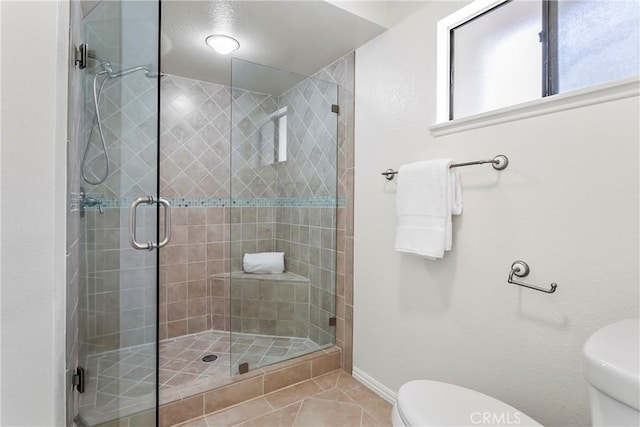 bathroom featuring an enclosed shower, tile patterned floors, and toilet