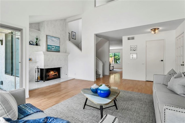 living room featuring a large fireplace, wood-type flooring, and vaulted ceiling