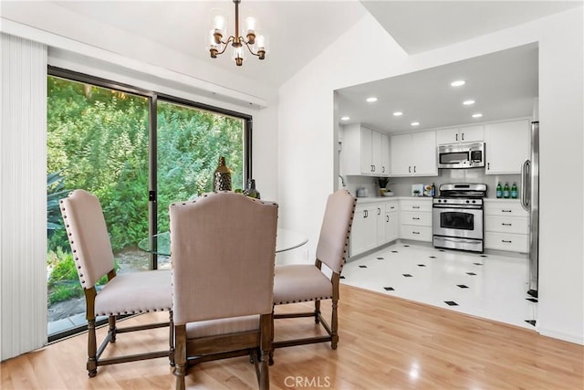 dining room with vaulted ceiling, an inviting chandelier, and light wood-type flooring