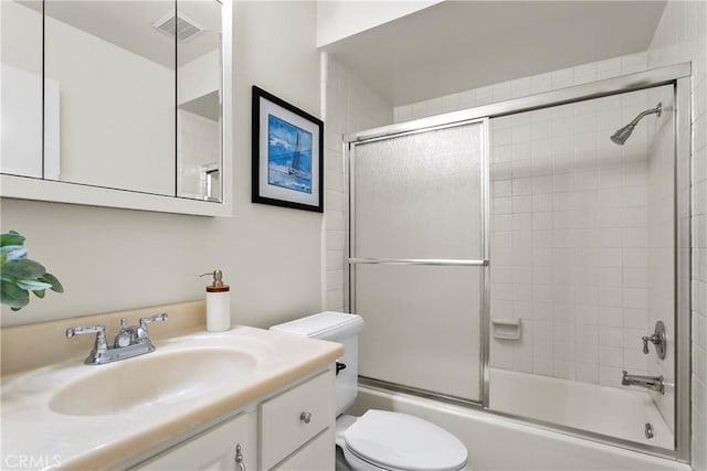 full bathroom featuring vanity, combined bath / shower with glass door, and toilet