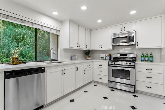 kitchen with stainless steel appliances, white cabinetry, sink, and light tile patterned flooring