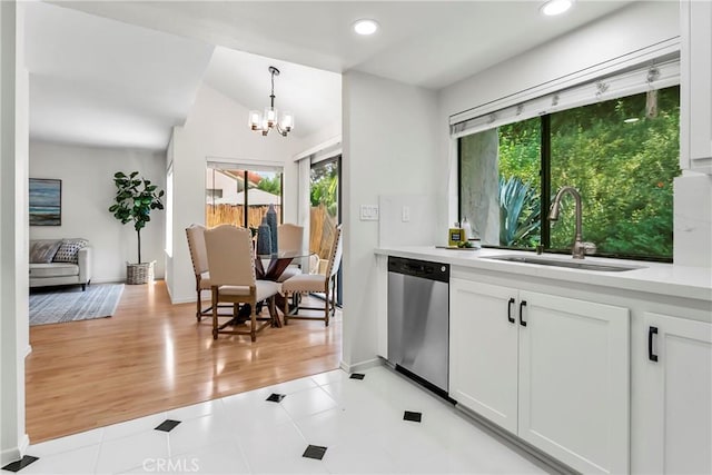 kitchen with pendant lighting, sink, light tile patterned floors, white cabinetry, and stainless steel dishwasher