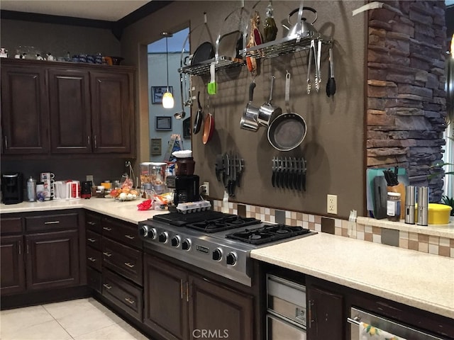 kitchen featuring light countertops, stainless steel gas stovetop, hanging light fixtures, light tile patterned flooring, and dark brown cabinets