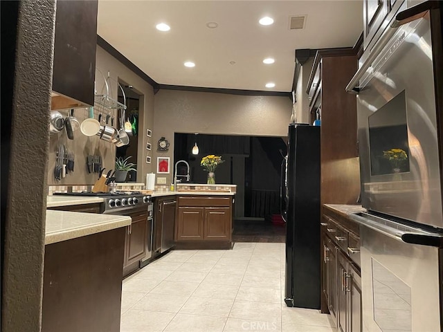 kitchen with visible vents, ornamental molding, dark brown cabinetry, appliances with stainless steel finishes, and light countertops