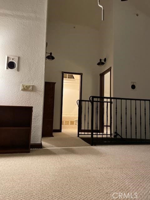 hallway featuring carpet and a towering ceiling