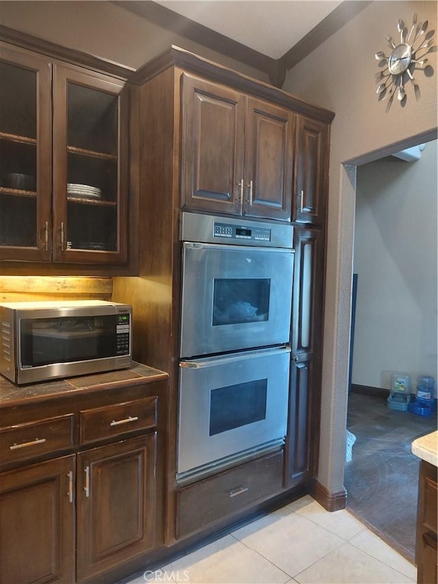 kitchen with dark brown cabinetry, light tile patterned flooring, baseboards, and appliances with stainless steel finishes