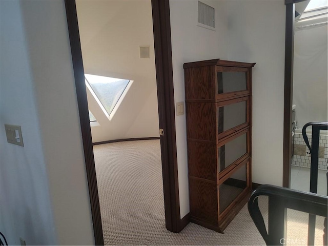 corridor with visible vents, baseboards, a skylight, and carpet flooring