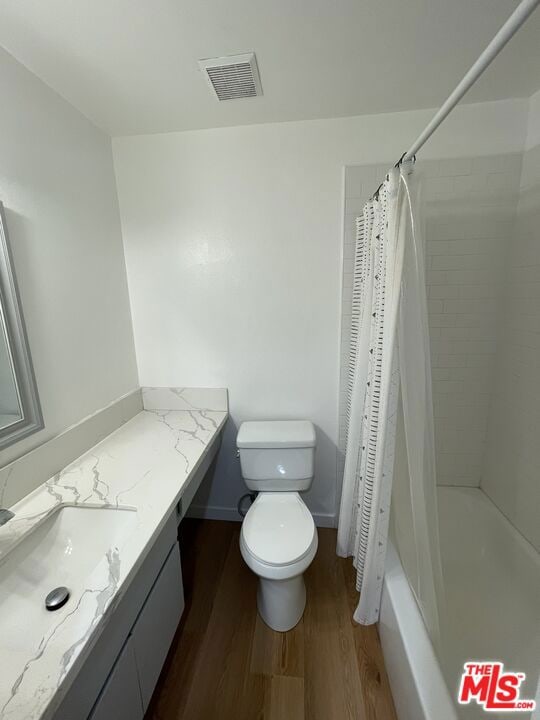 full bathroom with vanity, hardwood / wood-style floors, shower / bath combination with curtain, and toilet