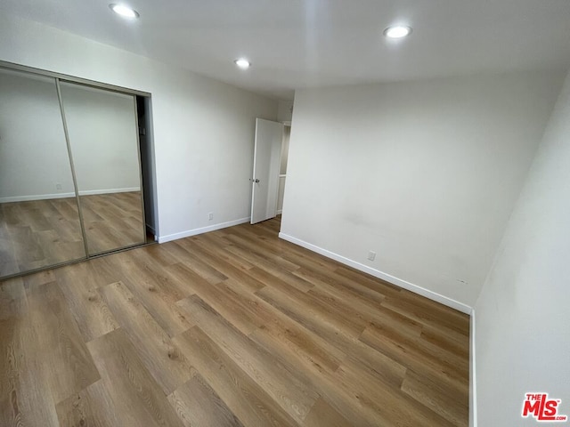 unfurnished bedroom with light wood-type flooring and a closet