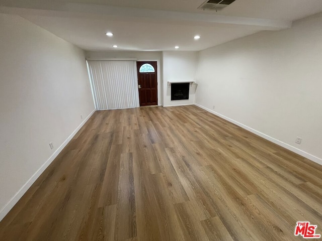 unfurnished living room featuring hardwood / wood-style flooring and beam ceiling