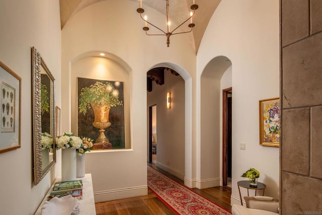 hallway featuring wood-type flooring, vaulted ceiling, and an inviting chandelier