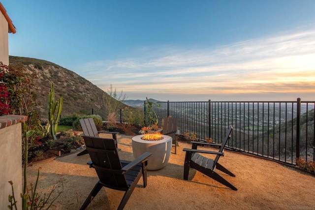 patio terrace at dusk featuring an outdoor fire pit and a mountain view