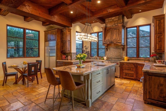 kitchen with sink, backsplash, premium appliances, wood ceiling, and a center island with sink