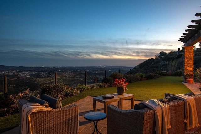 patio terrace at dusk featuring a lawn