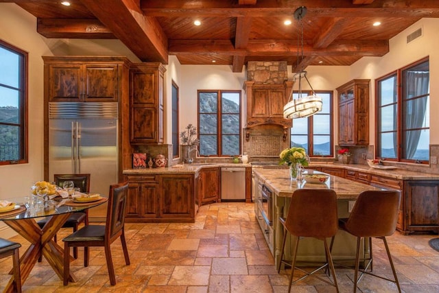 kitchen with pendant lighting, stainless steel appliances, a center island, light stone countertops, and wooden ceiling