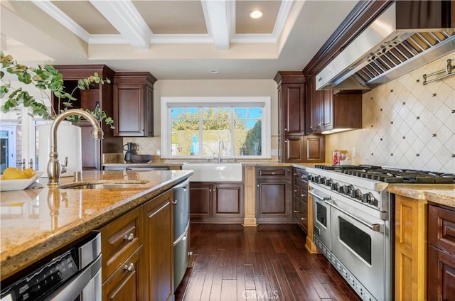 kitchen with tasteful backsplash, wall chimney exhaust hood, sink, and range with two ovens