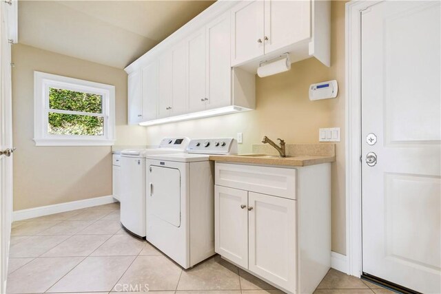 washroom with sink, light tile patterned floors, washer and clothes dryer, and cabinets