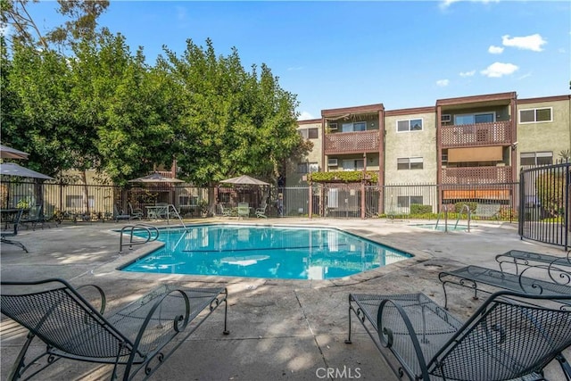 community pool with a patio area and fence