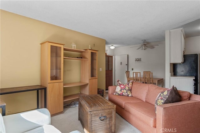 living area featuring a textured ceiling, a ceiling fan, and light carpet