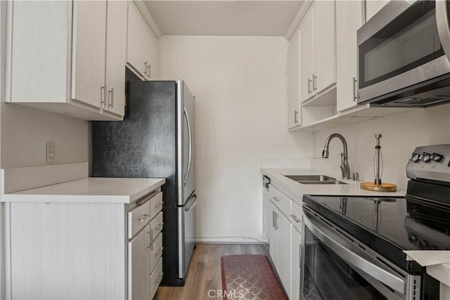 kitchen with a sink, appliances with stainless steel finishes, light wood-style flooring, and light countertops