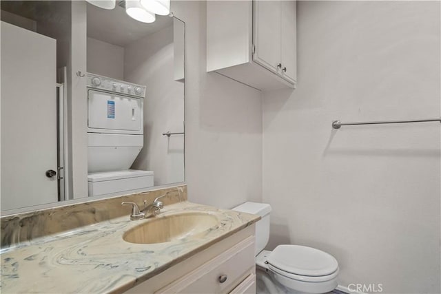 bathroom featuring vanity, stacked washer / drying machine, and toilet