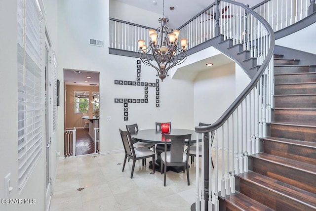 dining space featuring tile patterned floors, a chandelier, and a high ceiling