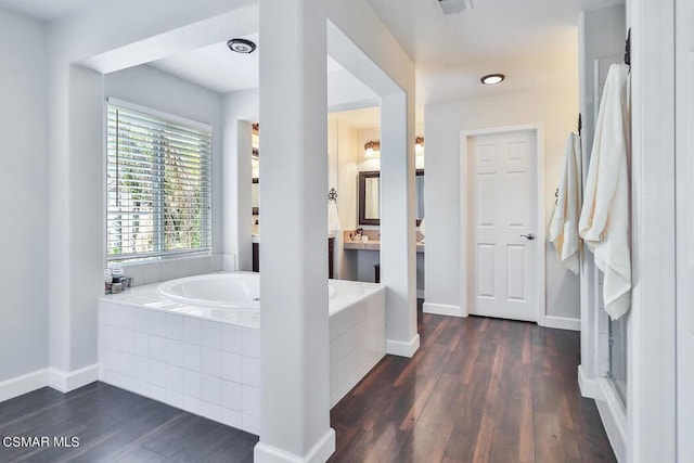 bathroom with hardwood / wood-style floors, vanity, and tiled bath